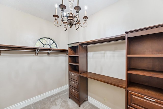 walk in closet featuring light colored carpet and an inviting chandelier