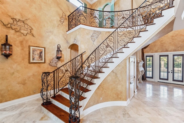 staircase with a high ceiling and french doors