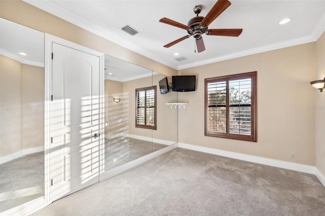 empty room featuring carpet flooring, crown molding, and ceiling fan