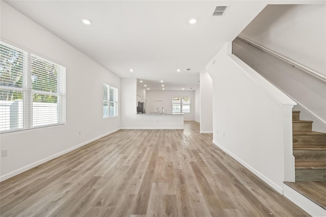 unfurnished living room with sink, plenty of natural light, and light hardwood / wood-style flooring