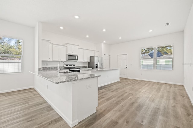 kitchen featuring white cabinets, appliances with stainless steel finishes, kitchen peninsula, and plenty of natural light