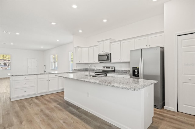 kitchen featuring white cabinets, sink, stainless steel appliances, and an island with sink