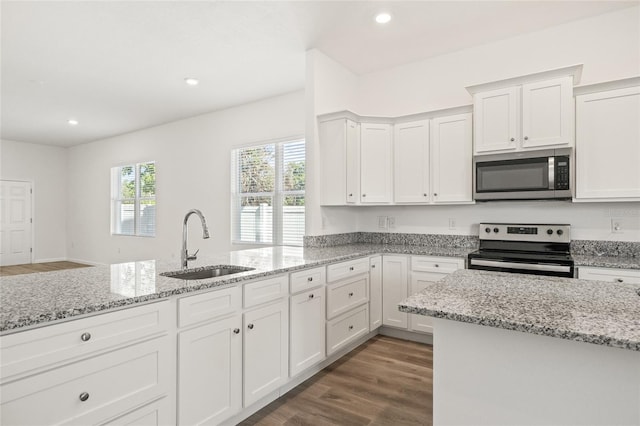 kitchen featuring light stone countertops, stainless steel appliances, dark wood-type flooring, sink, and white cabinetry