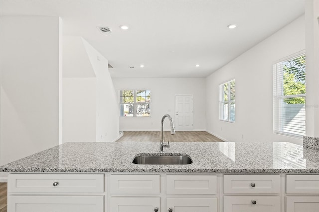 kitchen with white cabinets, sink, and a wealth of natural light