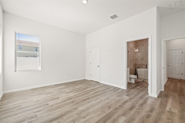 unfurnished bedroom with light hardwood / wood-style floors and ensuite bath