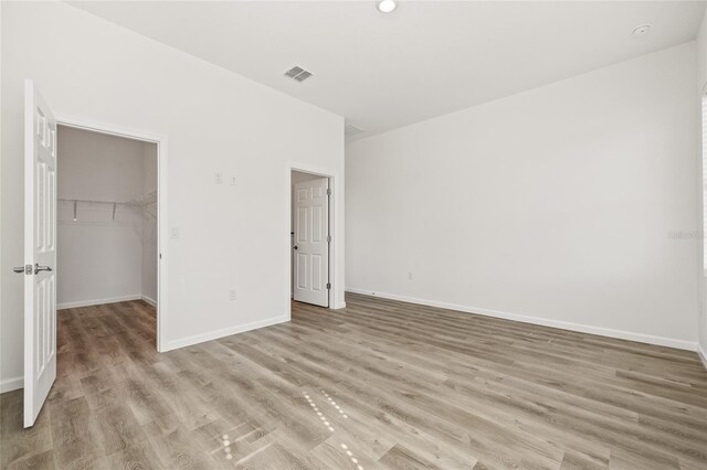 unfurnished bedroom with a walk in closet, light wood-type flooring, and a closet