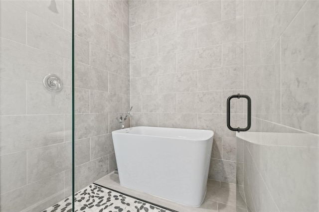 bathroom featuring tile patterned flooring, tile walls, and independent shower and bath