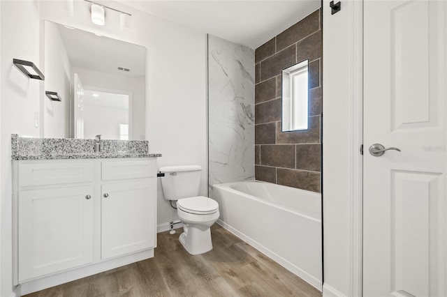 full bathroom with hardwood / wood-style floors, vanity, toilet, and tiled shower / bath