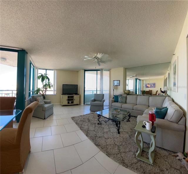 living room featuring light tile patterned floors, a textured ceiling, a wall of windows, and ceiling fan