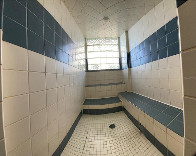 bathroom featuring walk in shower, tile patterned floors, and tile walls