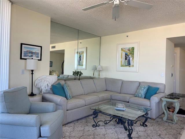 living room with carpet flooring, ceiling fan, and a textured ceiling