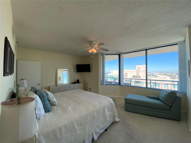 bedroom featuring ceiling fan, light colored carpet, and a textured ceiling