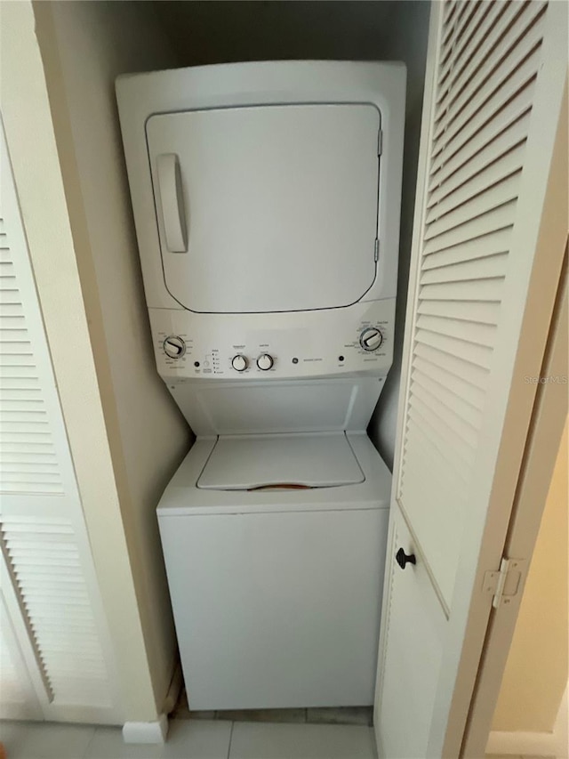 laundry area with light tile patterned floors and stacked washing maching and dryer