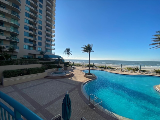 view of swimming pool featuring a patio area, a community hot tub, and a water view