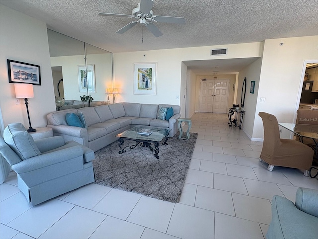 living room with ceiling fan, light tile patterned floors, and a textured ceiling