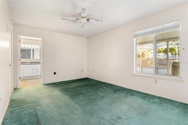 carpeted spare room with ceiling fan and a textured ceiling