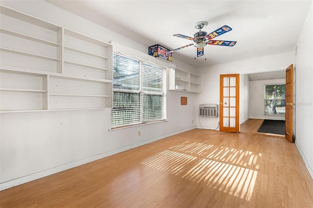 unfurnished living room featuring french doors, heating unit, a wall unit AC, ceiling fan, and light hardwood / wood-style floors