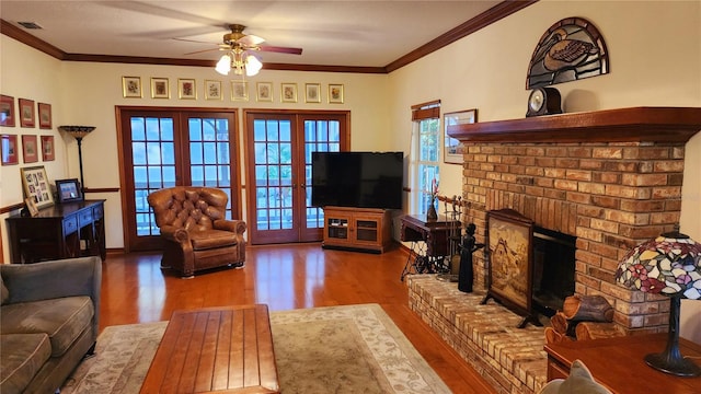 living room featuring hardwood / wood-style floors, french doors, a brick fireplace, ceiling fan, and ornamental molding