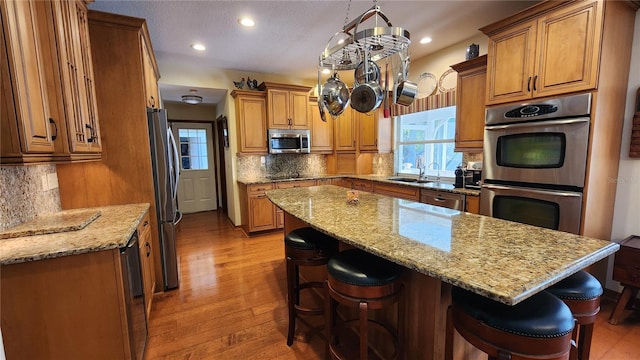 kitchen featuring tasteful backsplash, light stone countertops, a center island, and stainless steel appliances