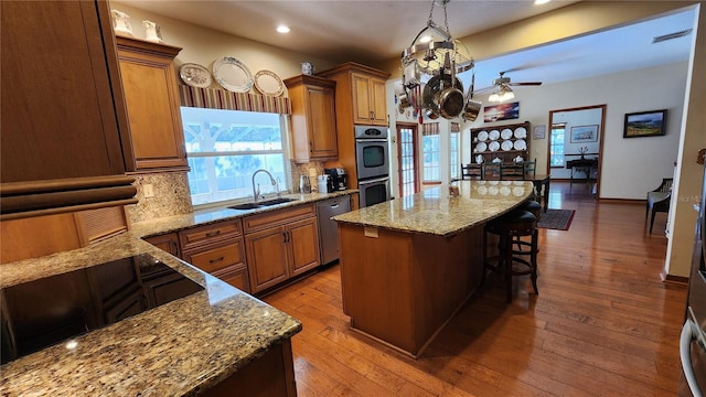 kitchen featuring a kitchen breakfast bar, sink, decorative light fixtures, light hardwood / wood-style flooring, and a center island