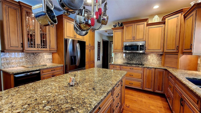 kitchen with light stone counters, light hardwood / wood-style flooring, tasteful backsplash, and black appliances