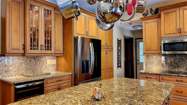 kitchen with appliances with stainless steel finishes, tasteful backsplash, light stone counters, a textured ceiling, and beverage cooler