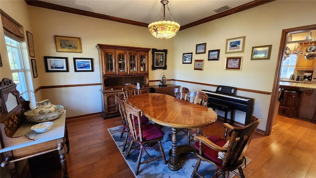 dining space featuring dark hardwood / wood-style floors, an inviting chandelier, and crown molding