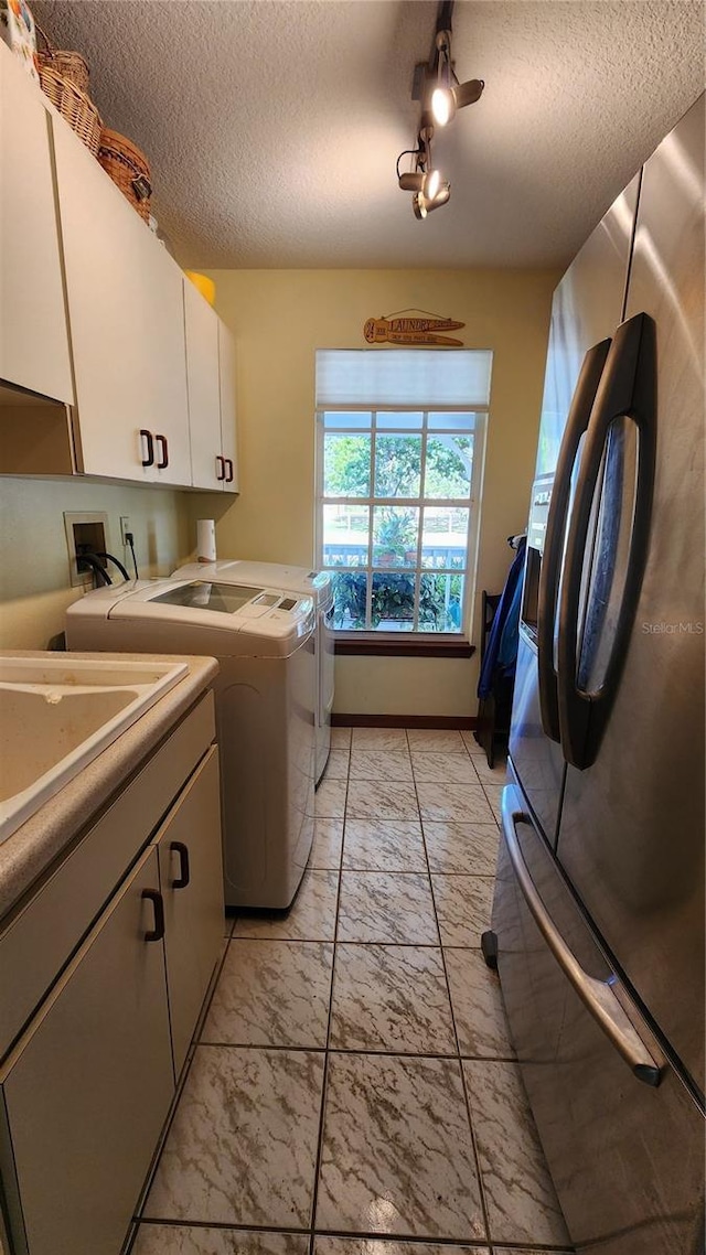 laundry area featuring cabinets, a textured ceiling, and washing machine and dryer