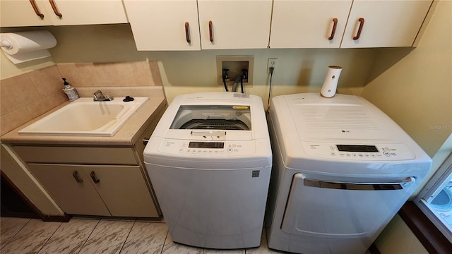 clothes washing area with separate washer and dryer, sink, and cabinets