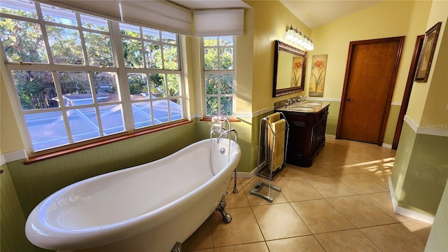 bathroom featuring tile patterned flooring, vanity, a bath, and lofted ceiling