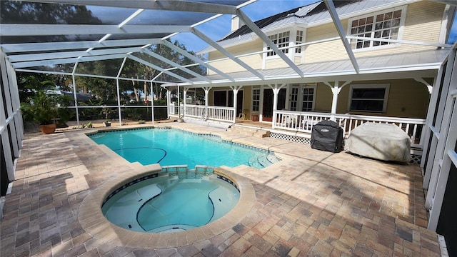 view of swimming pool with a lanai, a patio area, and an in ground hot tub