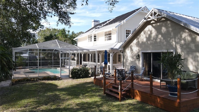 back of property with a swimming pool side deck, glass enclosure, and a lawn