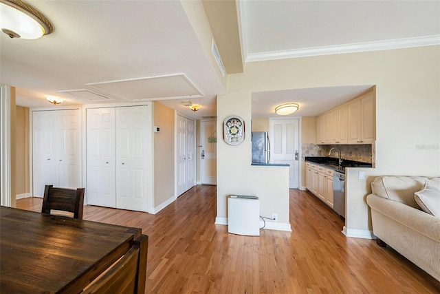 kitchen featuring stainless steel appliances, backsplash, light hardwood / wood-style floors, and ornamental molding