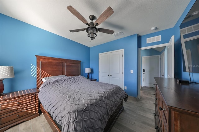 bedroom featuring a closet, ceiling fan, light hardwood / wood-style flooring, and a textured ceiling