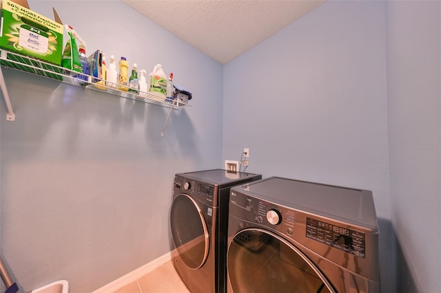 laundry area featuring light tile patterned flooring, a textured ceiling, and washing machine and clothes dryer