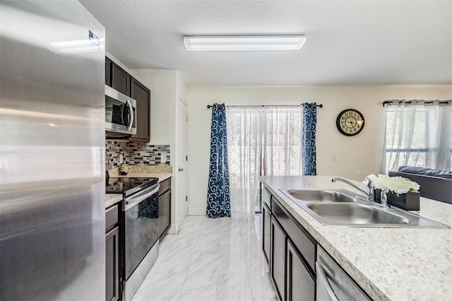 kitchen with backsplash, sink, stainless steel appliances, and a textured ceiling