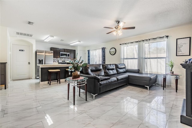 living room featuring ceiling fan and a textured ceiling