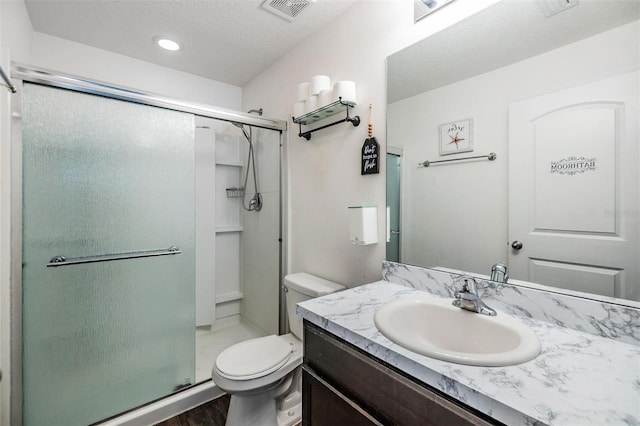 bathroom with vanity, hardwood / wood-style flooring, toilet, walk in shower, and a textured ceiling