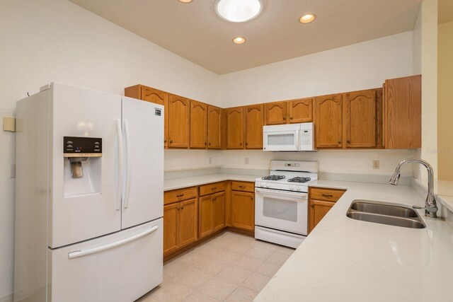 kitchen featuring white appliances, brown cabinetry, light countertops, and a sink