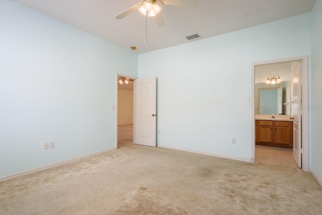 unfurnished bedroom featuring visible vents, ensuite bath, ceiling fan, a sink, and light colored carpet