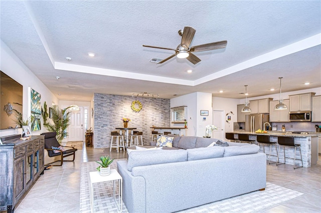 living room with light tile patterned floors, a textured ceiling, and a raised ceiling