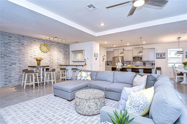 living room featuring ceiling fan and a textured ceiling