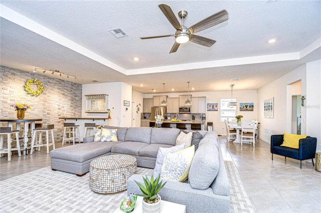 living room featuring a textured ceiling, ceiling fan, and light tile patterned flooring