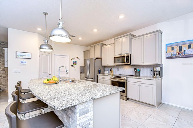 kitchen featuring light stone countertops, appliances with stainless steel finishes, backsplash, sink, and decorative light fixtures