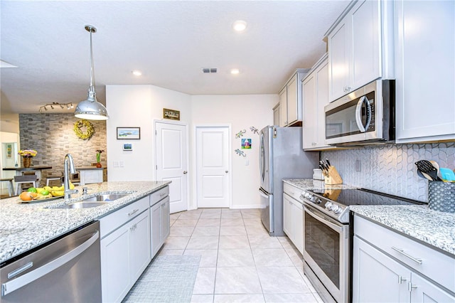 kitchen featuring decorative backsplash, sink, stainless steel appliances, and hanging light fixtures