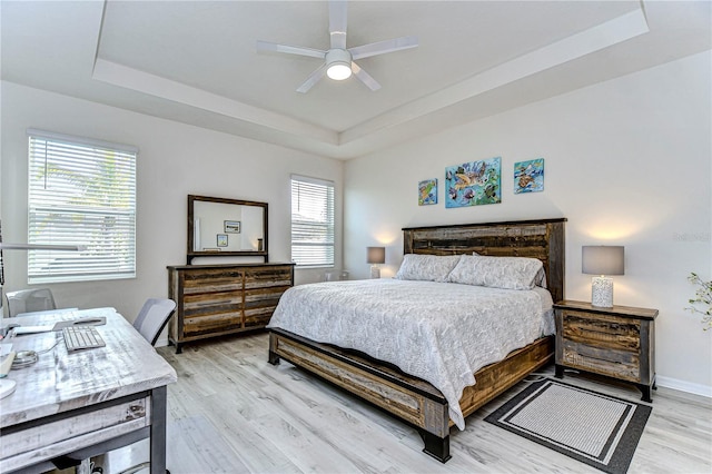 bedroom featuring a tray ceiling, ceiling fan, and light hardwood / wood-style floors