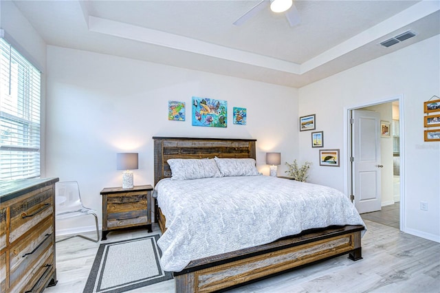 bedroom featuring a tray ceiling, ceiling fan, and light hardwood / wood-style floors