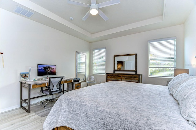 bedroom featuring a tray ceiling, ceiling fan, and light hardwood / wood-style floors