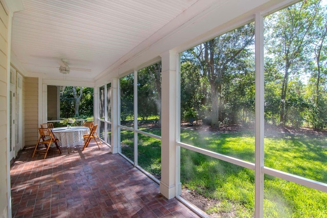 unfurnished sunroom featuring ceiling fan and a healthy amount of sunlight