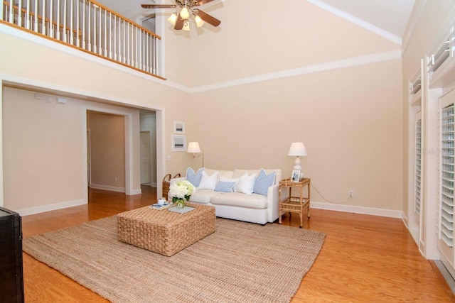 living room featuring hardwood / wood-style floors, ceiling fan, crown molding, and high vaulted ceiling